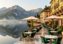 Grand Hotel Tremezzo's iconic lakefront terrace café overlooking the serene waters of Lake Como with Alpine mountains